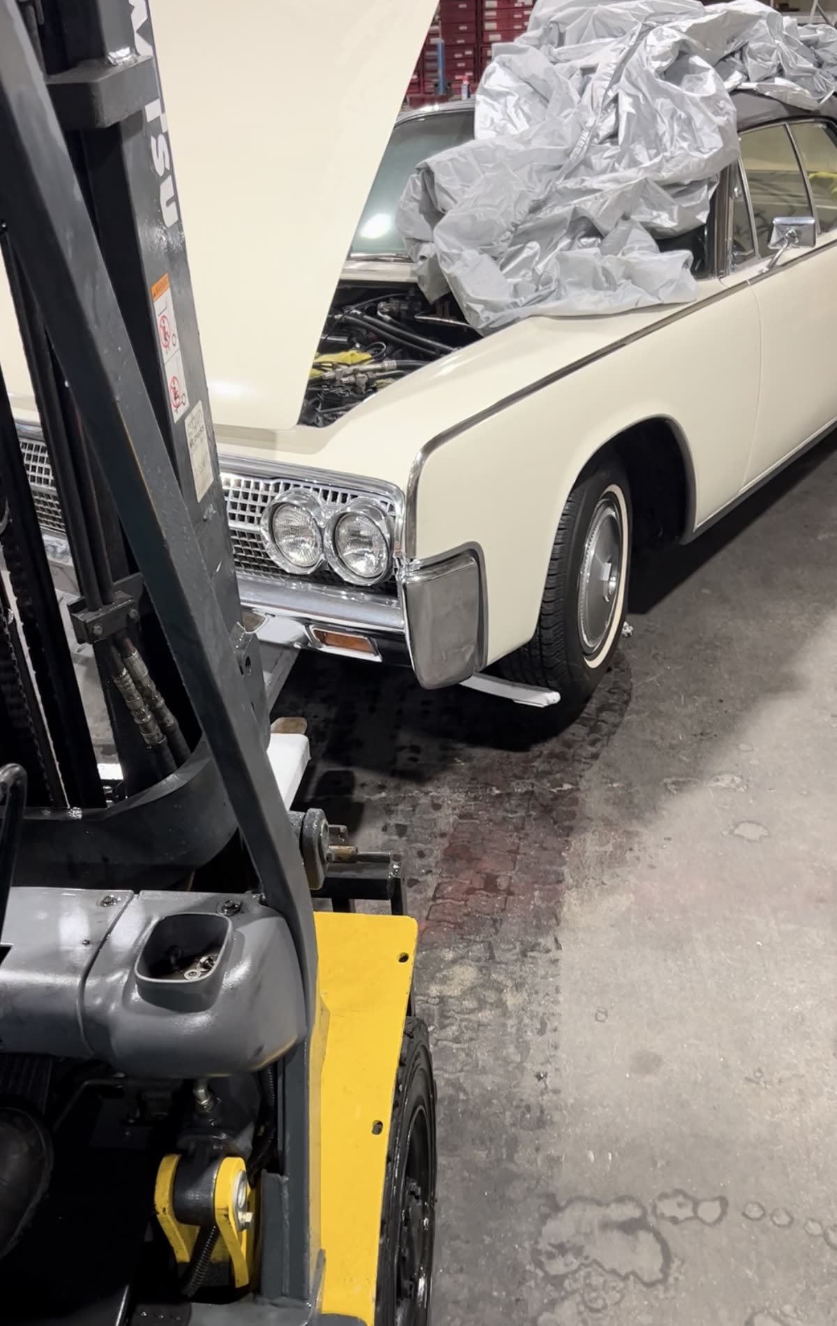Forklift with an Autowlift attachment carrying a classic car inside a warehouse