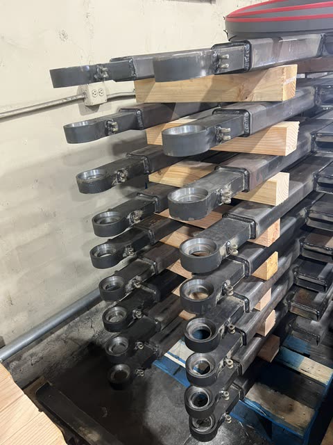 Rows of machined Autowlift lift arms racked before welding