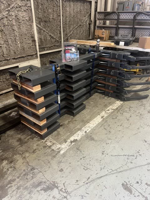 Finished Autowlift attachments and arm assemblies stacked in the Hawthorne shop